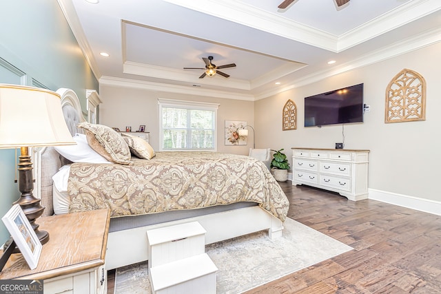 bedroom featuring dark wood-type flooring, a tray ceiling, crown molding, and ceiling fan