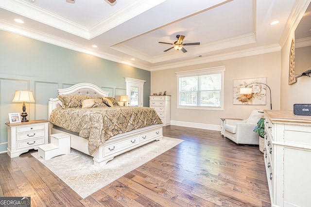 bedroom with crown molding, ceiling fan, dark wood-type flooring, and a tray ceiling