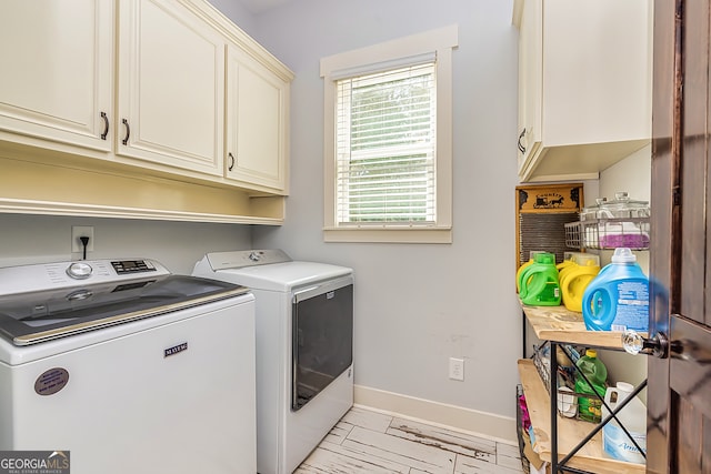 clothes washing area featuring washing machine and dryer and cabinets