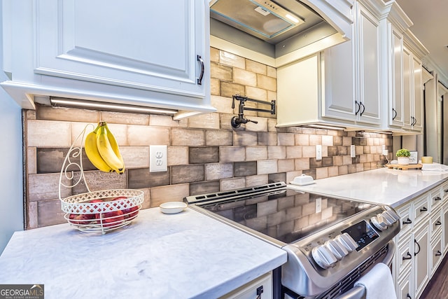 kitchen with stainless steel electric range oven, decorative backsplash, and white cabinetry