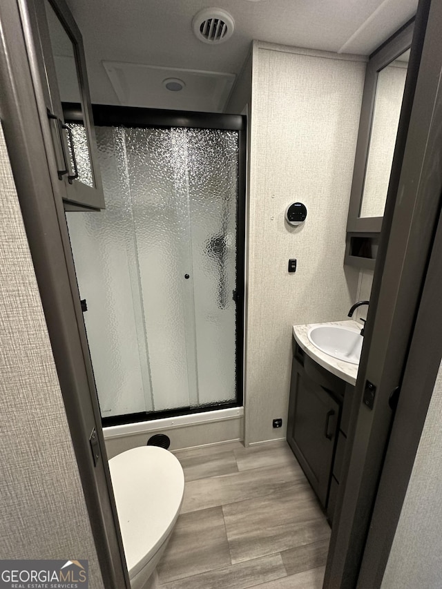 bathroom featuring walk in shower, toilet, vanity, and hardwood / wood-style flooring