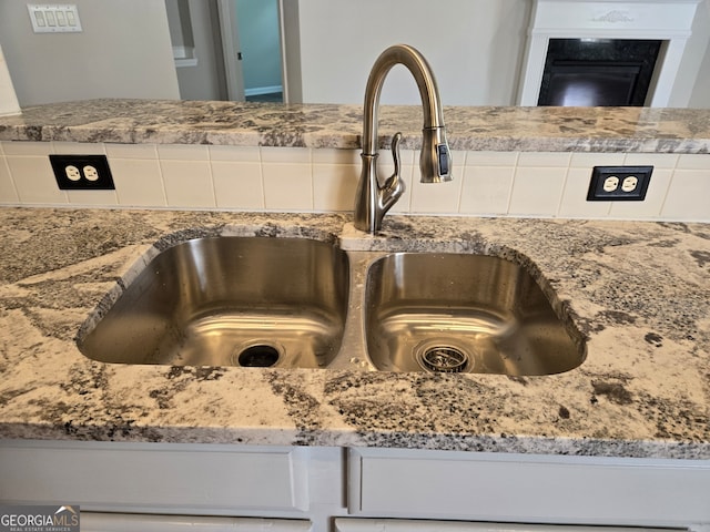 interior details featuring light stone countertops, white cabinets, and sink