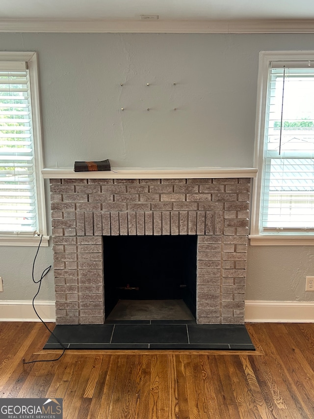 interior details with ornamental molding, a brick fireplace, and hardwood / wood-style flooring