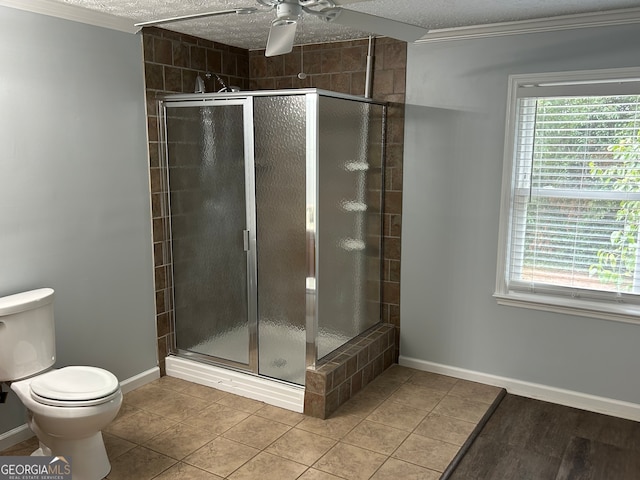 bathroom with a textured ceiling, tile patterned flooring, ceiling fan, a shower with door, and toilet