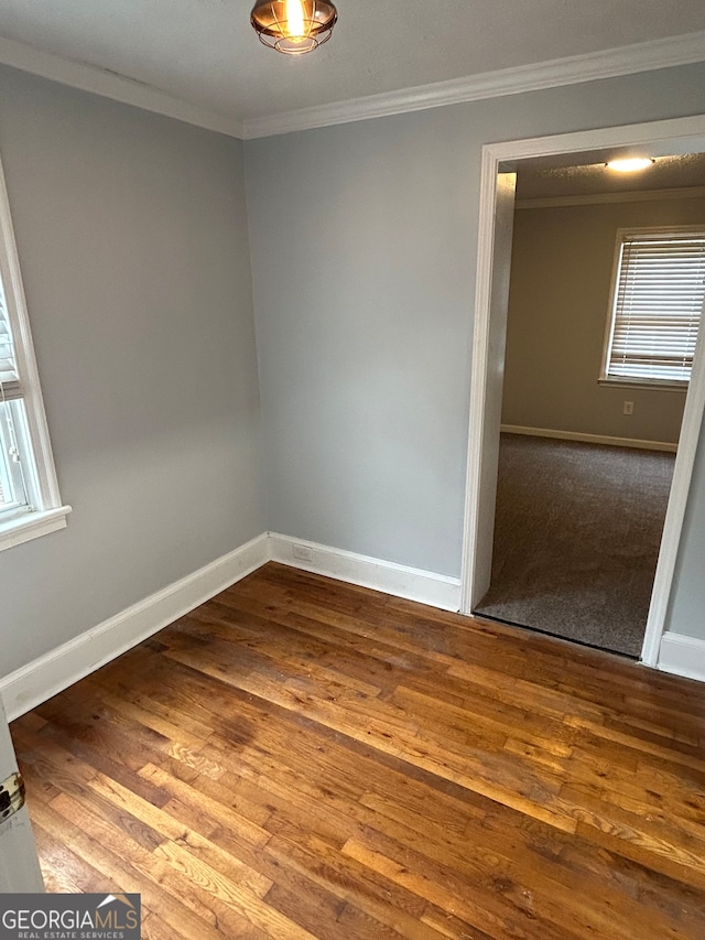 empty room featuring ornamental molding and hardwood / wood-style floors