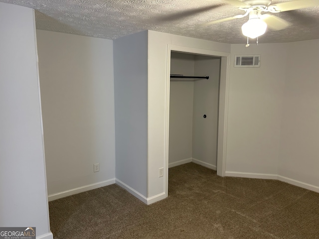 unfurnished bedroom featuring a textured ceiling, dark colored carpet, and ceiling fan