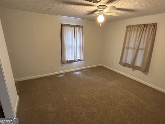 spare room featuring dark colored carpet, ceiling fan, and a textured ceiling