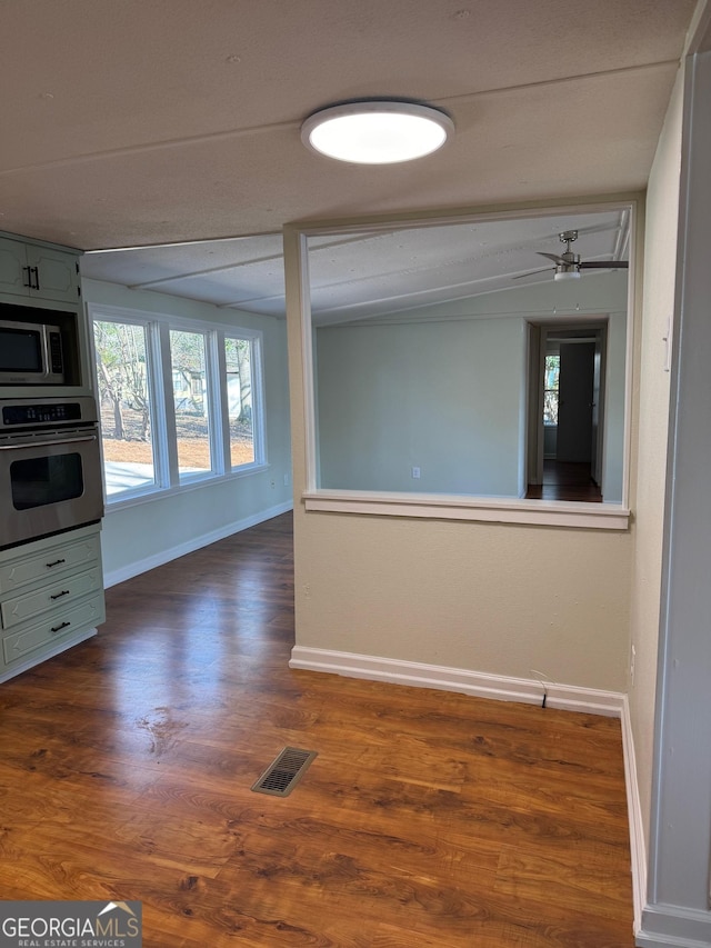 empty room with a wealth of natural light and dark hardwood / wood-style flooring