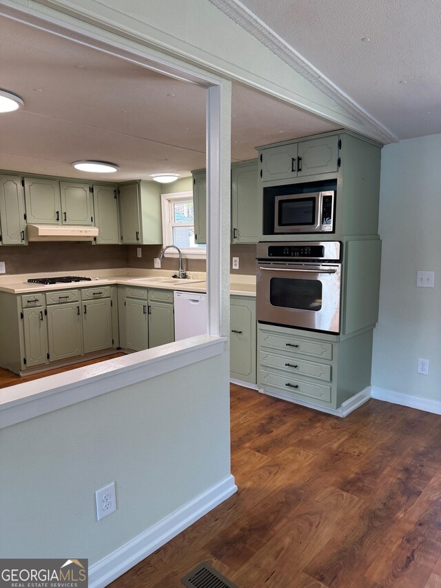 kitchen featuring sink, green cabinetry, stainless steel appliances, dark wood-type flooring, and a textured ceiling