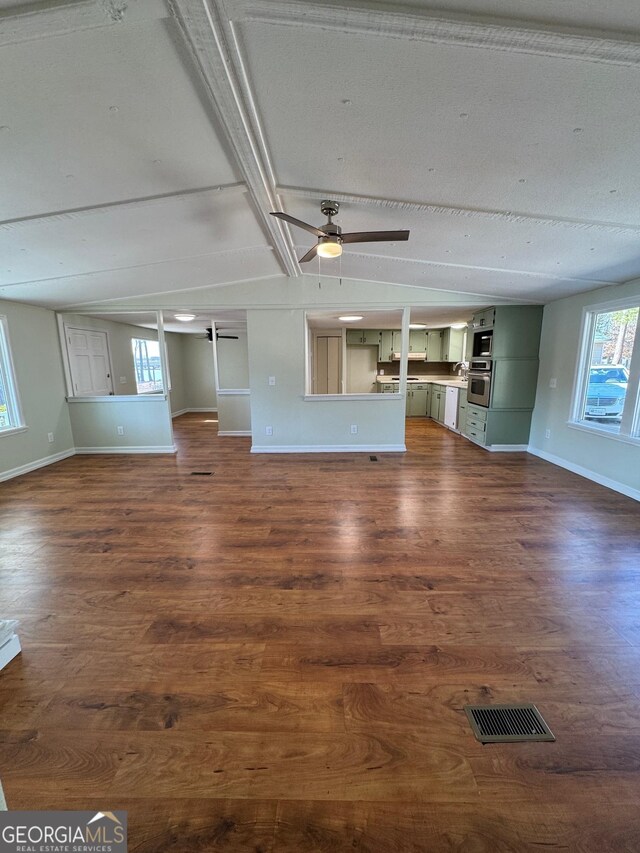 unfurnished living room featuring lofted ceiling with beams, dark hardwood / wood-style floors, and ceiling fan