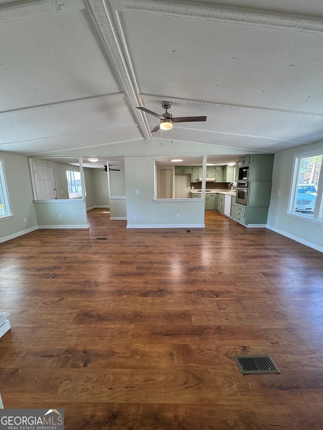 unfurnished living room with dark wood-style floors, baseboards, and ceiling fan