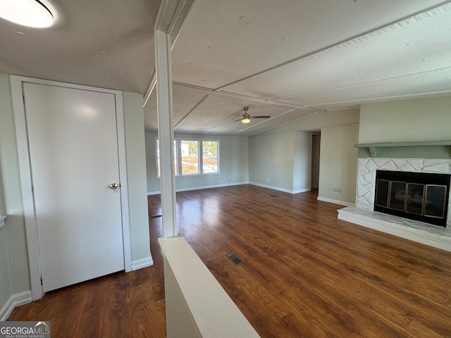 unfurnished living room with a glass covered fireplace, wood finished floors, baseboards, and a ceiling fan