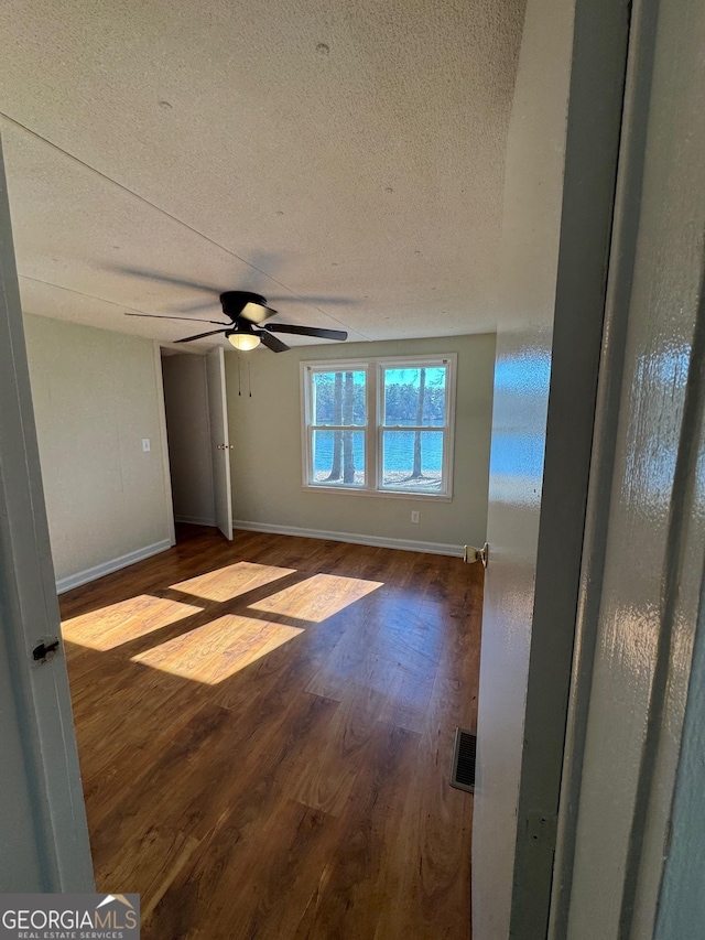 empty room with ceiling fan, hardwood / wood-style floors, and a textured ceiling