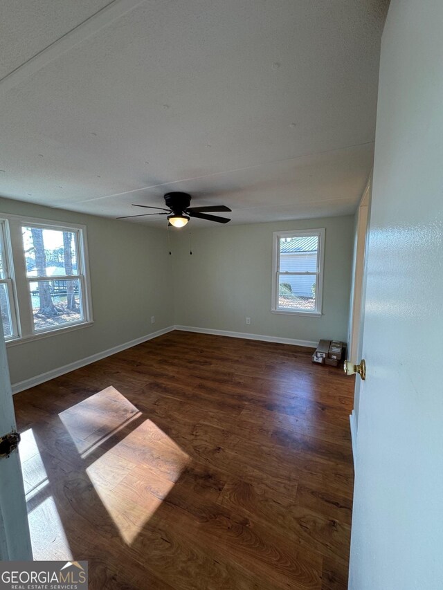 empty room featuring dark hardwood / wood-style flooring, plenty of natural light, and ceiling fan