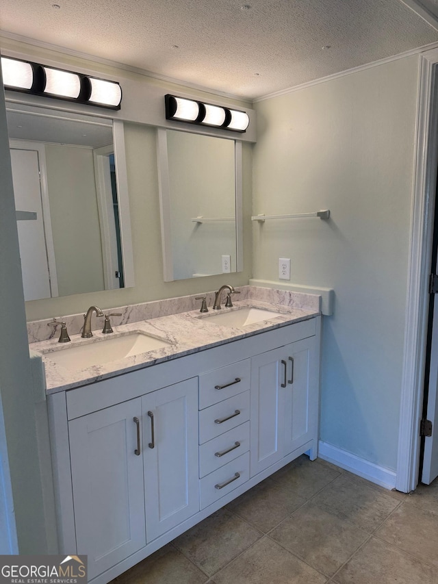 bathroom featuring double vanity, a textured ceiling, crown molding, and a sink