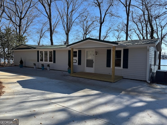 ranch-style house with metal roof, central AC unit, and a porch