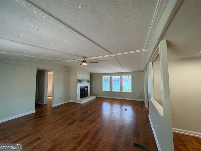 unfurnished living room with ceiling fan, lofted ceiling, dark hardwood / wood-style flooring, and a textured ceiling