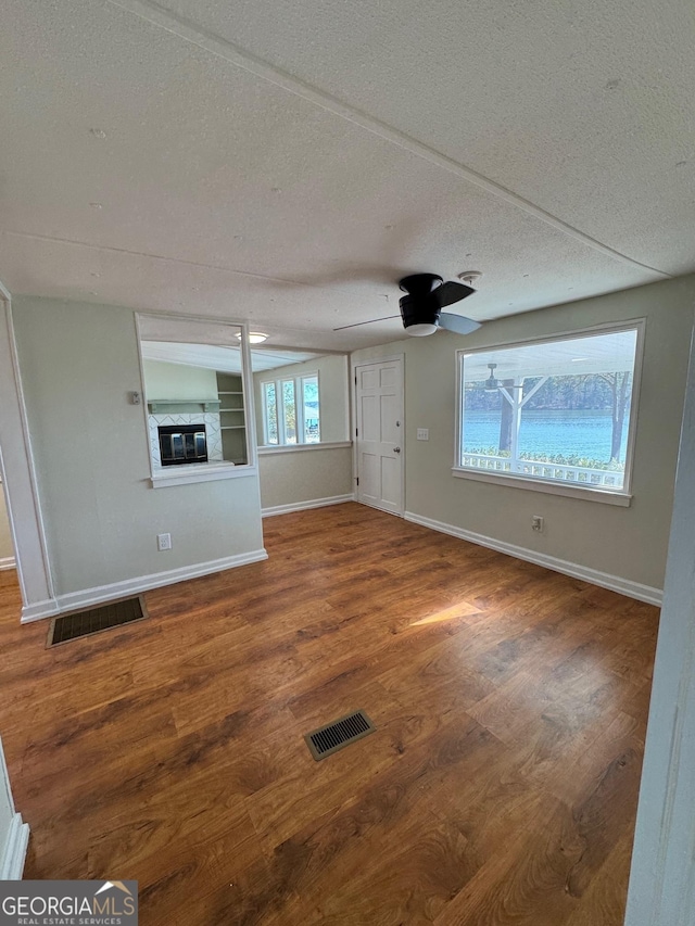 unfurnished living room featuring ceiling fan, hardwood / wood-style floors, and a textured ceiling