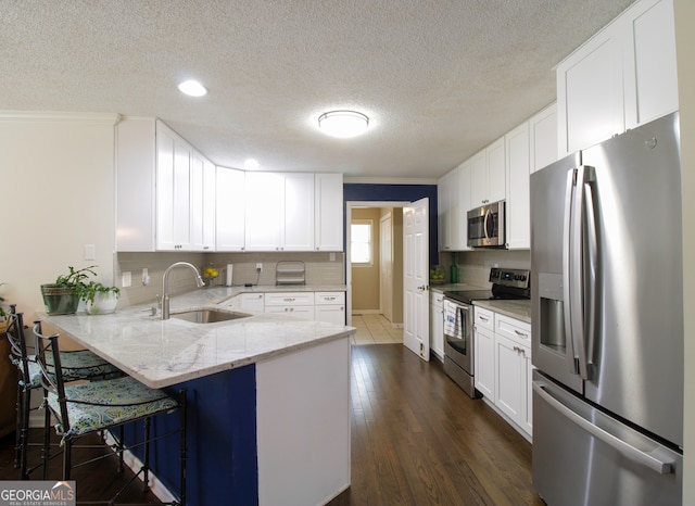 kitchen featuring dark hardwood / wood-style floors, a breakfast bar area, white cabinets, kitchen peninsula, and stainless steel appliances