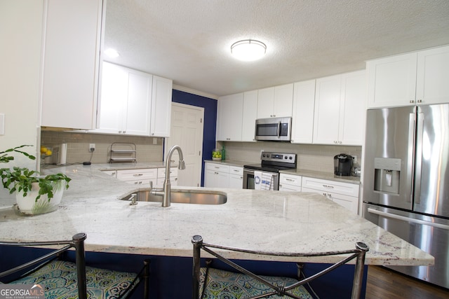 kitchen with sink, white cabinetry, kitchen peninsula, a kitchen breakfast bar, and stainless steel appliances