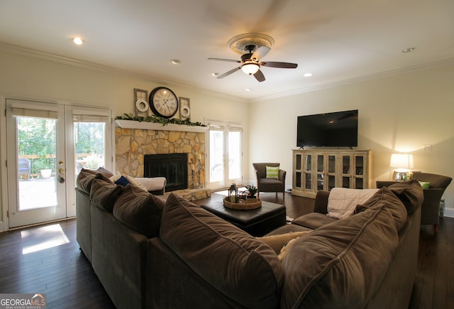 living room with ceiling fan, a stone fireplace, dark hardwood / wood-style floors, and ornamental molding