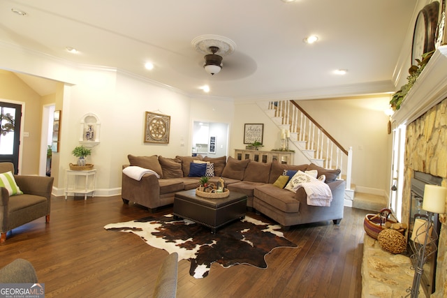 living room featuring crown molding, a fireplace, dark hardwood / wood-style flooring, and ceiling fan