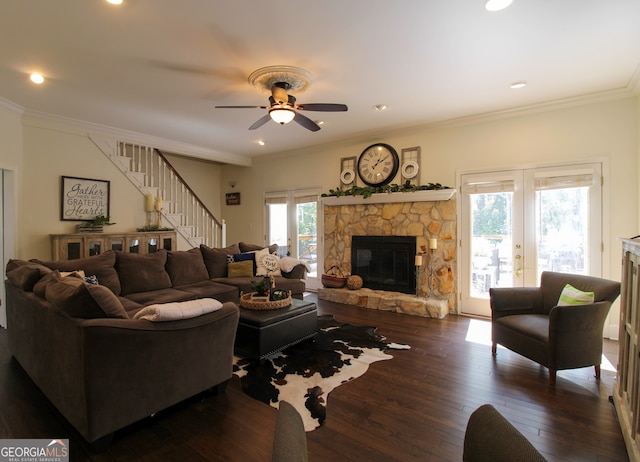 living room with a stone fireplace, crown molding, ceiling fan, french doors, and dark hardwood / wood-style floors