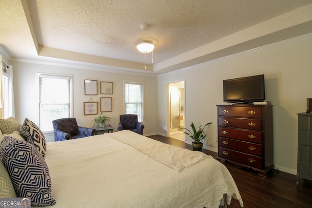 bedroom with dark hardwood / wood-style floors, a raised ceiling, ensuite bathroom, crown molding, and ceiling fan