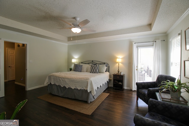 bedroom with a textured ceiling, a tray ceiling, ceiling fan, ornamental molding, and dark hardwood / wood-style floors