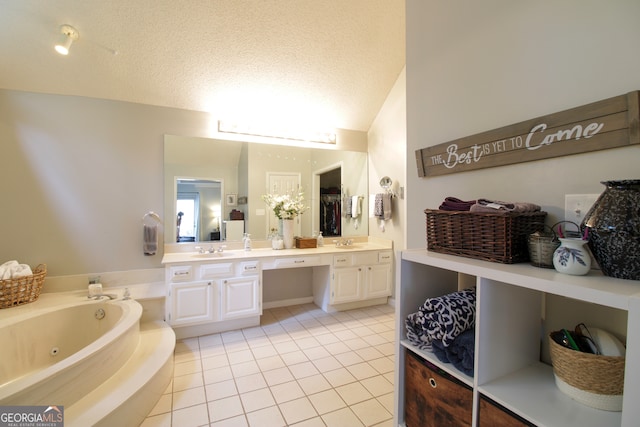 bathroom featuring tiled tub, vanity, a textured ceiling, lofted ceiling, and tile patterned floors