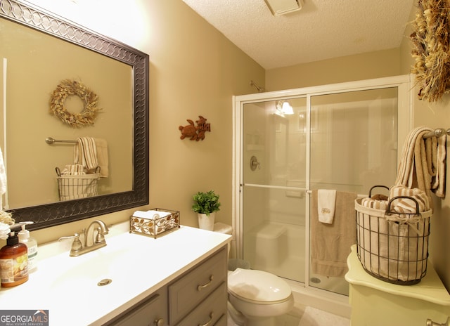 bathroom featuring a textured ceiling, walk in shower, vanity, and toilet