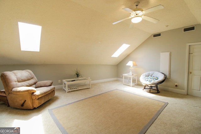 living area with vaulted ceiling with skylight, carpet flooring, and ceiling fan