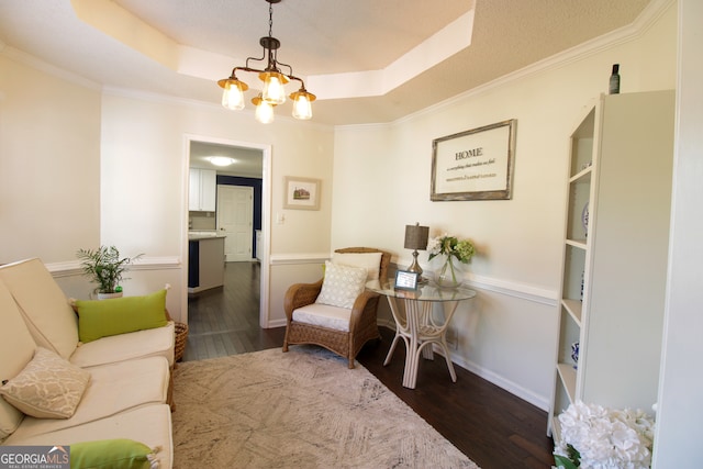 sitting room with ornamental molding, a chandelier, a raised ceiling, and dark hardwood / wood-style floors