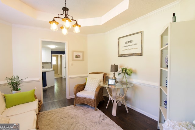 living area with ornamental molding, dark wood-type flooring, and a chandelier