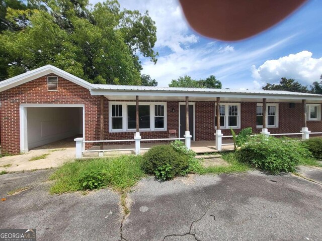 single story home featuring a porch and a garage