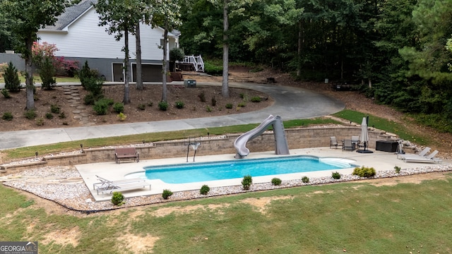 view of swimming pool featuring a yard, a water slide, and a patio area