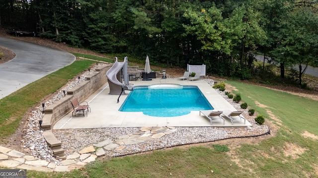 view of pool with a water slide, a patio area, and a yard