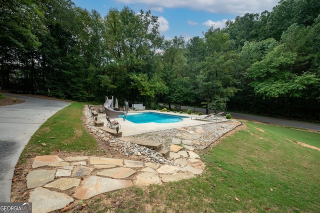 view of pool with a patio, a lawn, and a water slide