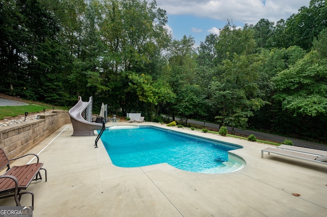 view of swimming pool featuring a water slide and a patio area