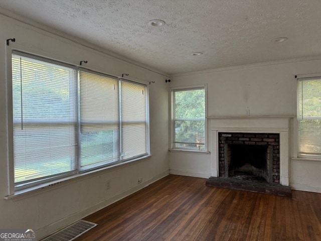 unfurnished living room with ornamental molding, a brick fireplace, a textured ceiling, and dark hardwood / wood-style flooring