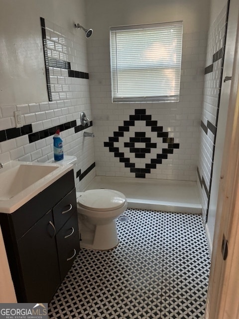 bathroom featuring vanity, toilet, tiled shower, tile patterned flooring, and decorative backsplash