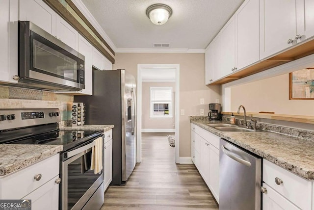 kitchen featuring sink, white cabinets, light hardwood / wood-style flooring, stainless steel appliances, and crown molding