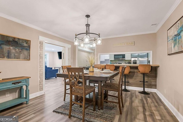 dining room featuring an inviting chandelier, hardwood / wood-style flooring, and ornamental molding