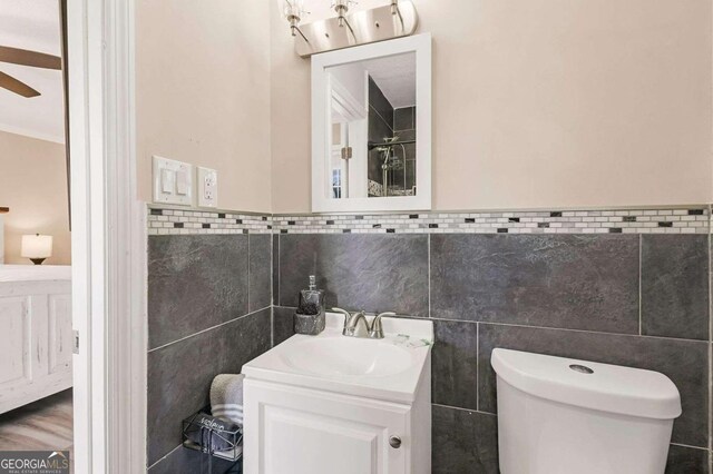 bathroom with ornamental molding, tile walls, vanity, and toilet