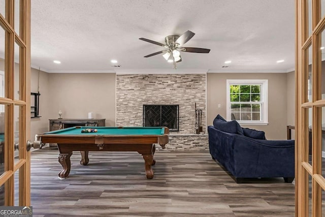 game room with pool table, a stone fireplace, hardwood / wood-style floors, and ceiling fan