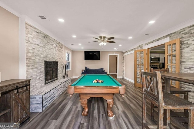 playroom featuring a stone fireplace, dark hardwood / wood-style flooring, ceiling fan, pool table, and ornamental molding