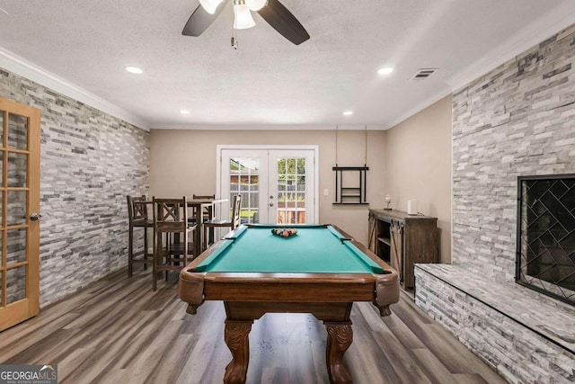 recreation room with wood-type flooring, billiards, a stone fireplace, ceiling fan, and french doors