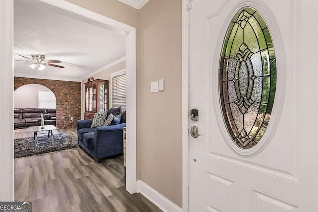 entryway with wood-type flooring, ceiling fan, and crown molding