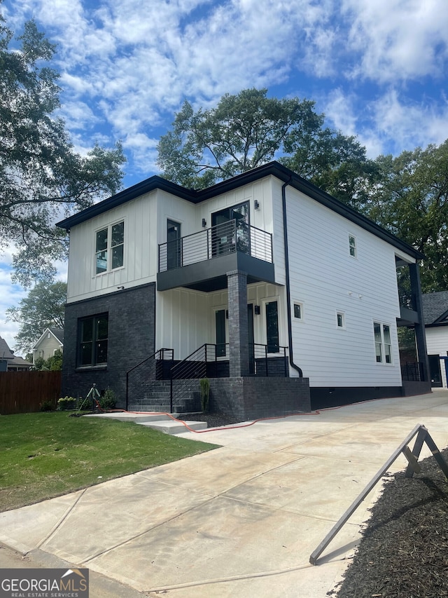 view of front of home with a balcony and a front lawn