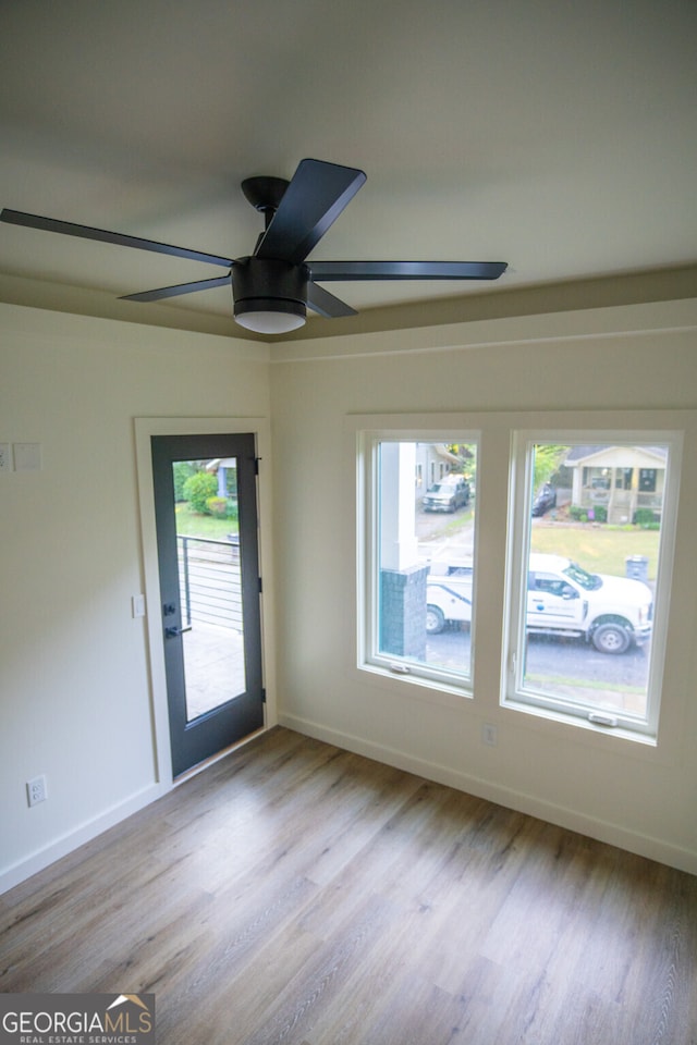 empty room with a healthy amount of sunlight, ceiling fan, and light hardwood / wood-style flooring